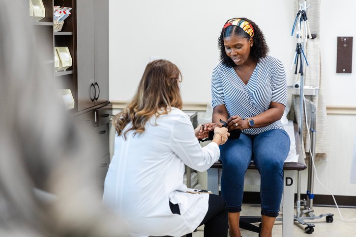 Unrecognizable female ER doctor helps mature woman with orthopedic brace